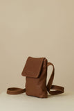 Brown leather bag on a white pedestal against a wooden background