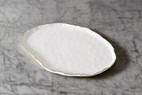 White ceramic plate with gold rim on a light gray background
