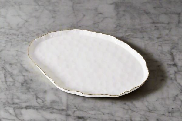 White ceramic plate with gold rim on a light gray background
